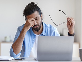 Exhausted man with sleep apnea struggling to work