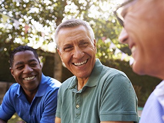 group of smiling men sitting outside