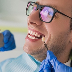 Man in glasses smiles while getting dental implants