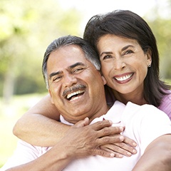 Smiling couple holding each other while sitting outside