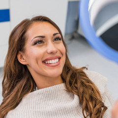 Woman smiling at reflection in handheld mirror