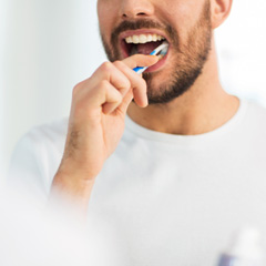 Man smiling while brushing his teeth