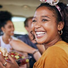 Woman smiling while eating lunch with friends on road trip
