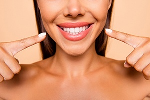 A woman pointing to her new and improved smile that is sporting veneers in Ponte Vedra Beach