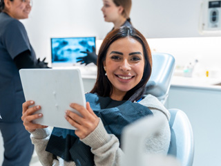 Woman smiling while holding mirror in treatment chair