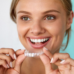 Smiling patient holding teeth whitening tray