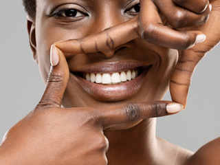 Closeup of woman framing white smile with her hands