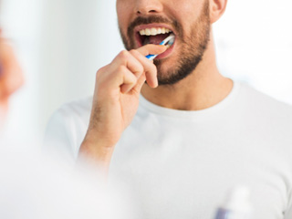Man in white shirt brushing his teeth