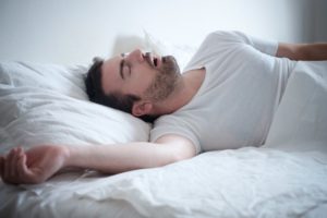 A man snoring in bed.