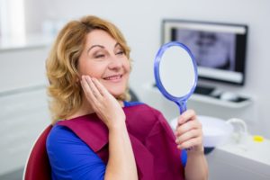 Patient admiring smile after denture to implant transition