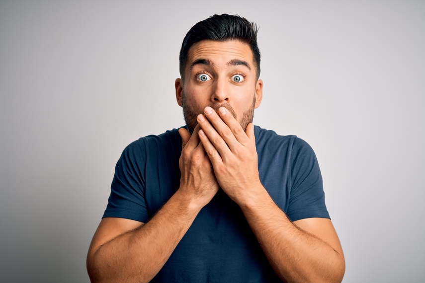 man shocked with hands over mouth