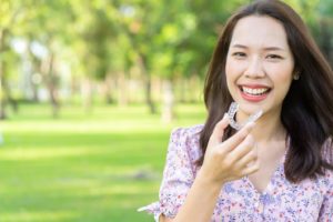 Woman smiling and holding her Invisalign tray.