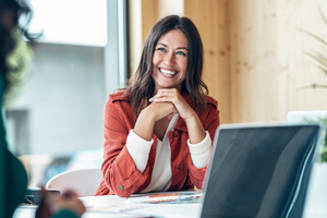 Woman at work sitting in front of computer and smiling