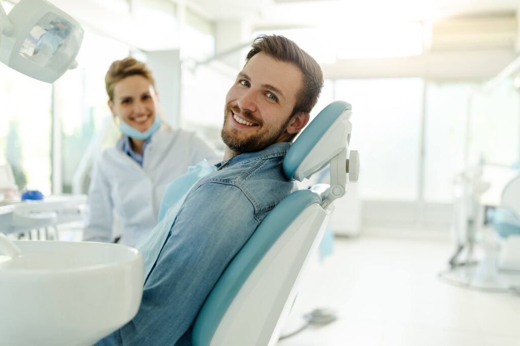 Man smiling while sitting in treatment room with dentist